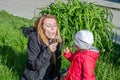 Young beautiful mother with adorable little daughter Baby girl with long hair Europeans in a meadow with grass and flowers