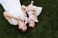 Young beautiful mother and baby girl playing and having fun on grass at summer. mom and child are lying down on ground Royalty Free Stock Photo