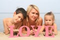 Young beautiful mother with children lying on the beach with word Love