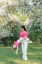 A young beautiful mother is happy and holding her daughter in her arms, they are having fun in the spring park Royalty Free Stock Photo