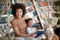 A young beautiful mother and her cute little daughter posing while sitting on the swing and reading a book at home together. Royalty Free Stock Photo