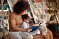 A young beautiful mother and her cute little daughter sitting on the swing and reading a book at home together. Family, together, Royalty Free Stock Photo