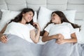 Young beautiful mother and her cute teen daughter just woke up together in bed smiling to each other Royalty Free Stock Photo