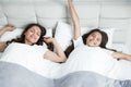 Young beautiful mother and her cute teen daughter just woke up together stretching in bed Royalty Free Stock Photo