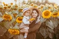 Young beautiful mother and her little cute son walk in a field with sunflowers, have fun, run and have fun together Royalty Free Stock Photo