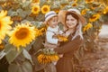 Young beautiful mother and her little cute son walk in a field with sunflowers, have fun, run and have fun together Royalty Free Stock Photo