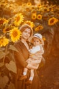 Young beautiful mother and her little cute son walk in a field with sunflowers, have fun, run and have fun together Royalty Free Stock Photo