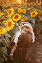 Young beautiful mother and her little cute son walk in a field with sunflowers, have fun, run and have fun together Royalty Free Stock Photo