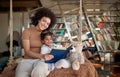 A young beautiful mother and her little daughter enjoying a book sitting on the swing at home together. Family, together, leisure Royalty Free Stock Photo