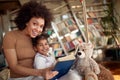 A young beautiful mother and her little daughter are full of joy while posing on the swing at home together. Family, together, Royalty Free Stock Photo