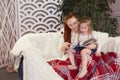 Young beautiful mother with her little daughter reading a book sitting on the couch. Royalty Free Stock Photo