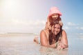 Young beautiful mother and her little girl in pink hat enjoying the ocean and relaxing at the tropical beach during sunny day Royalty Free Stock Photo