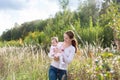 Young beautiful mother holding a baby girl wearing a pink dress in a meadow Royalty Free Stock Photo