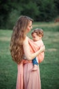 Young beautiful mother hugging her little toddler son against green grass. Happy woman with her baby boy on a summer Royalty Free Stock Photo