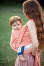 Young beautiful mother hugging her little toddler son against green grass. Happy woman with her baby boy on a summer Royalty Free Stock Photo