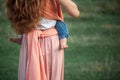 Young beautiful mother hugging her little toddler son against green grass. Happy woman with her baby boy on a summer Royalty Free Stock Photo