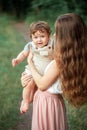 Young beautiful mother hugging her little toddler son against green grass. Happy woman with her baby boy on a summer Royalty Free Stock Photo