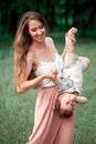 Young beautiful mother hugging her little toddler son against green grass. Happy woman with her baby boy on a summer Royalty Free Stock Photo