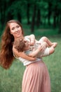 Young beautiful mother hugging her little toddler son against green grass. Happy woman with her baby boy on a summer Royalty Free Stock Photo