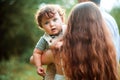 Young beautiful mother hugging her little toddler son against green grass. Happy woman with her baby boy on a summer Royalty Free Stock Photo