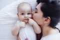 Young beautiful mother kisses her cute baby on cheek. Caucasian brunette touches her smiling child with her face Royalty Free Stock Photo