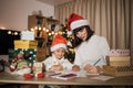 Young beautiful mother and little cute child daughter in red hats writing letter to Santa Claus Royalty Free Stock Photo