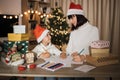 Young beautiful mother and little cute child daughter in red hats writing letter to Santa Claus Royalty Free Stock Photo