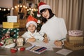 Young beautiful mother and little cute child daughter in red hats writing letter to Santa Claus Royalty Free Stock Photo