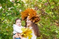 Young beautiful mother in a maple leaf wreath holding a sweet baby girl Royalty Free Stock Photo