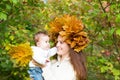 Young beautiful mother in a maple leaf wreath holding a sweet baby girl Royalty Free Stock Photo