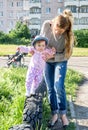 Young beautiful mother playing with her daughter on the playground in the grass sitting on wheels Royalty Free Stock Photo