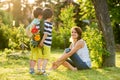 Young beautiful mother, sitting in a garden, little boys, her so Royalty Free Stock Photo