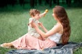 Young beautiful mother sitting with her little son against green grass. Happy woman with her baby boy on a summer sunny Royalty Free Stock Photo