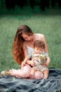 Young beautiful mother sitting with her little son against green grass. Happy woman with her baby boy on a summer sunny Royalty Free Stock Photo