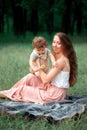 Young beautiful mother sitting with her little son against green grass. Happy woman with her baby boy on a summer sunny Royalty Free Stock Photo