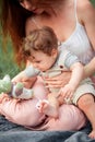 Young beautiful mother sitting with her little son against green grass. Happy woman with her baby boy on a summer sunny Royalty Free Stock Photo