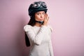 Young beautiful motorcyclist woman with blue eyes wearing moto helmet over pink background hand on mouth telling secret rumor, Royalty Free Stock Photo