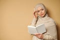 Young beautiful muslim woman in hijab looking to the side with a pensive look holding a white notepad and a pencil at her temple Royalty Free Stock Photo