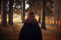 Young beautiful and mysterious woman in woods, in black cloak with hood, image of forest elf or witch, back Royalty Free Stock Photo