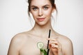 Young beautiful naked girl with perfect clean skin smiling looking at camera holding glass of water with cucumber slices Royalty Free Stock Photo