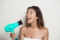 Young beautiful naked girl in towel singing with hairdryer. Royalty Free Stock Photo