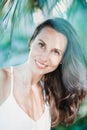 Young beautiful natural cheerful woman with healthy face and skin in exotic greenery. Closeup fresh face of attractive Royalty Free Stock Photo