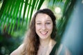 Young beautiful natural cheerful woman with healthy face and skin in exotic greenery. Closeup fresh face of attractive Royalty Free Stock Photo