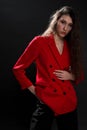 A young beautiful oriental woman with long black hair in a red jacket against a black background. The fashion model Royalty Free Stock Photo