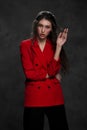 A young beautiful oriental woman with long black hair in a red jacket against a black background. The fashion model Royalty Free Stock Photo