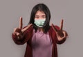 Young beautiful pacifist Asian Chinese woman in face mask doing peace fingers symbol standing for human rights respect and freedom