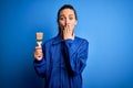 Young beautiful painter woman with blue eyes painting wearing uniform using paint brush cover mouth with hand shocked with shame Royalty Free Stock Photo