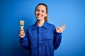 Young beautiful painter woman with blue eyes painting wearing uniform using paint brush doing ok sign with fingers, excellent Royalty Free Stock Photo