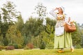 Young beautiful peasant woman with a bouquet of sunflowers in purse or basket looks far away Royalty Free Stock Photo