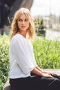 Young beautiful pensive blonde girl sitting on bench in park Royalty Free Stock Photo